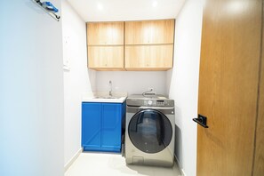 Cocina compacta con armarios de madera, lavadora y un mueble azul.