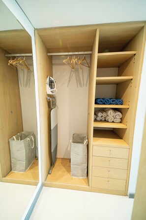 Un armario de madera con estantes, espacio para colgar ropa y un planchar incorporado.