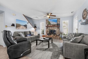 A living room with a fireplace, two sofas, a coffee table, and a ceiling fan. - Shelley by the Seas  Beach Escape in N. Myrtle Beach, 3-bedroom house (North Myrtle Beach)