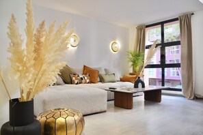 A modern living room with a sofa, coffee table, and decorative plants. - M17—Elegant Duplex in Majorelle—Pool, Balcony, and Parking (Marrakech)