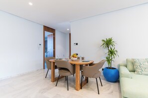 A modern living room with a dining area, a blue potted plant, and a light-colored sofa. - Family Canopy · Bright 3-bedroom apartment, 2 balconies, garage – Casablanca (Casablanca)