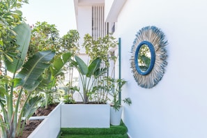 A modern outdoor space with a white wall, a blue decorative mirror, and various potted plants. - Family Canopy · Bright 3-bedroom apartment, 2 balconies, garage – Casablanca (Casablanca)
