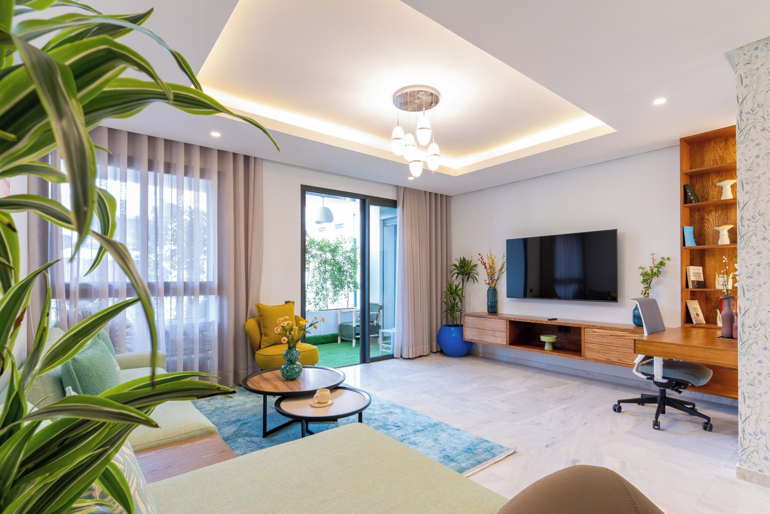 Una sala de estar moderna con televisor de pantalla plana, una mesa de centro, un sofá y una estantería.