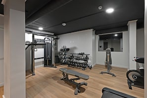 Une salle de sport équipée d’un banc, d’haltères et d’appareils d’exercice.