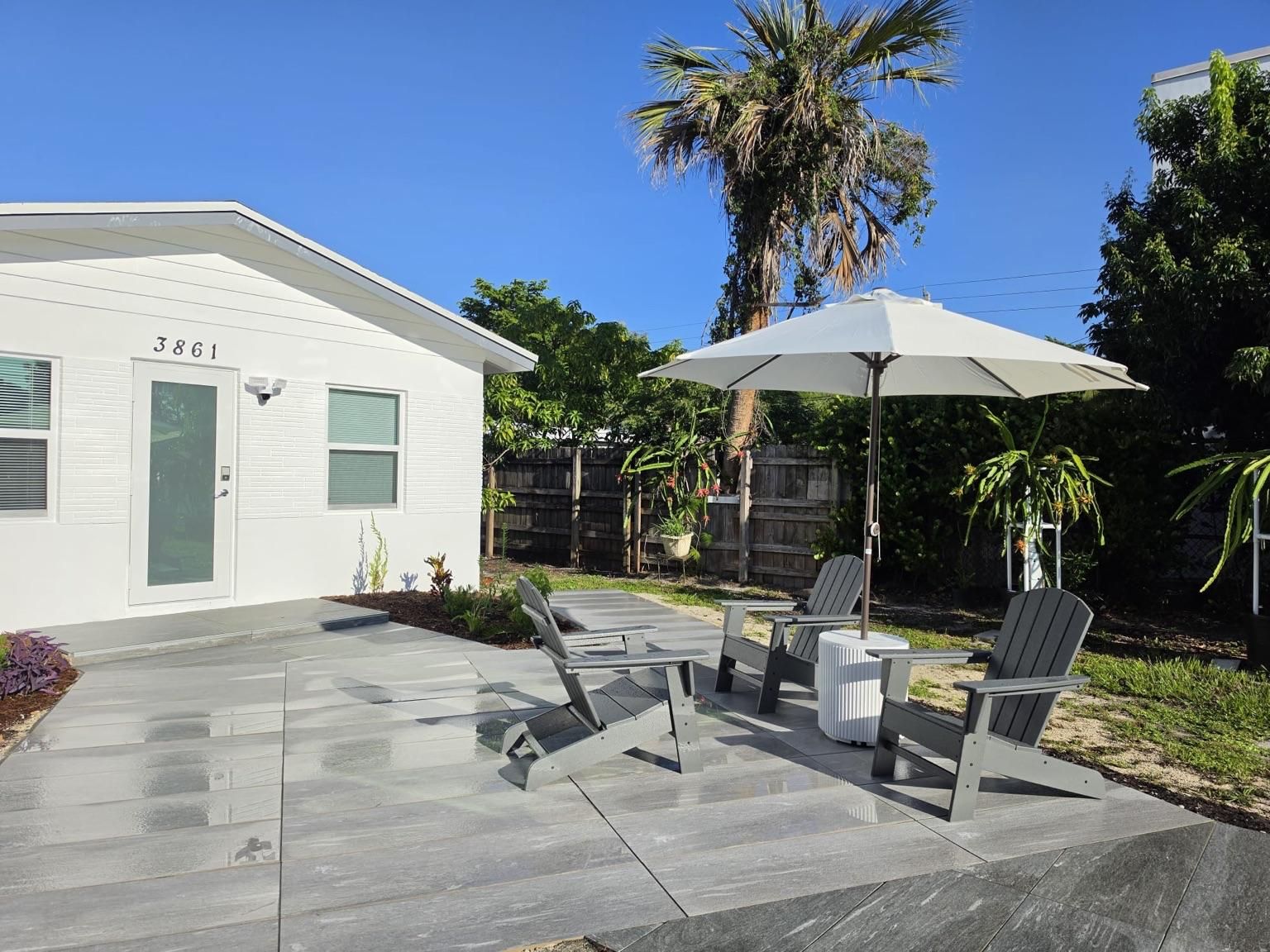 A modern house with a patio area featuring outdoor furniture and a large umbrella.