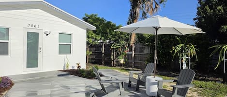 A modern house with a patio area featuring outdoor furniture and a large umbrella.