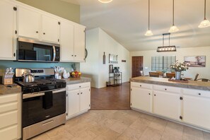 Una cocina con armarios blancos, estufa de acero inoxidable y microondas.