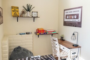 A room with a bed, a desk with a lamp, shelves with books and a clock, and a sign on the wall. - River Views + Fire Pit + Paso Robles Wine Country Views (Paso Robles)
