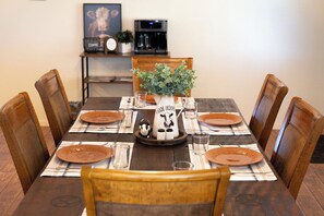 Mesa de comedor para cuatro personas, con platos marrones, vasos y un adorno central.