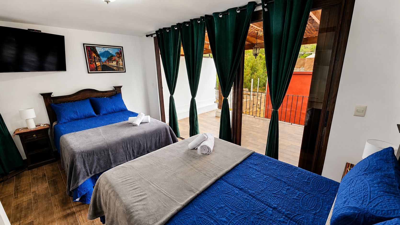 Ein Hotelzimmer mit zwei Betten, einem Fernseher und einem Balkon mit Vorhängen.