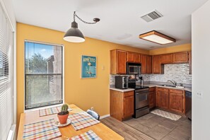 A modern kitchen with wooden cabinets, stainless steel appliances, and a large window with blinds. - Cozy 1-bedroom condo in the beautiful Catalina Foothills of Tucson. (Tucson)