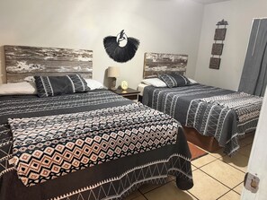 A room with two beds, each with patterned bedding, a wall-mounted decoration, and a door with a handle. - 2-bedroom campground in beautiful Leakey with cozy outdoor vibes (Leakey)