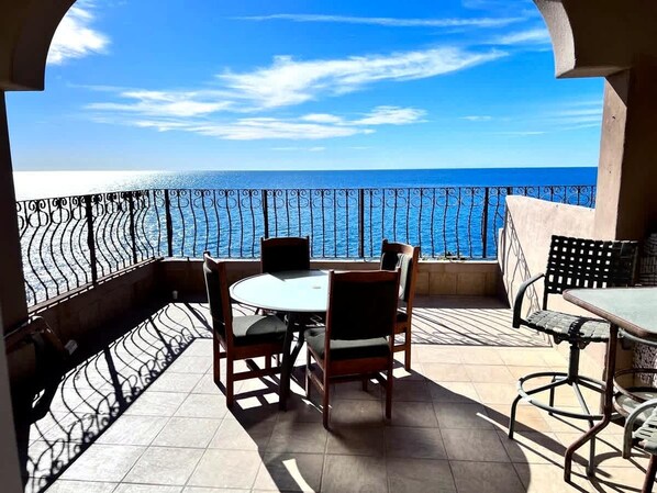 Un balcón con vistas al mar, amueblado con una mesa y sillas.