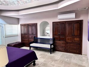 Un dormitorio con cama, un banco y un armario.
