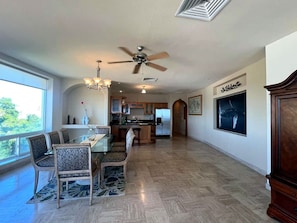 A spacious living area with a dining table, chairs, a ceiling fan, and a kitchen in the background. - Puerto Viejo C-3 | Waterfront 3BR on the Malecón (Puerto Peñasco)