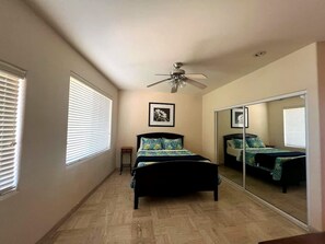 A bedroom with a bed, a ceiling fan, a small table, and a large mirror. - Puerto Viejo C-3 | Waterfront 3BR on the Malecón (Puerto Peñasco)