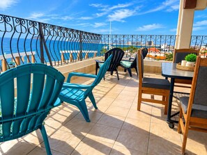 Een terras met stoelen en een tafel, met uitzicht op de kust.