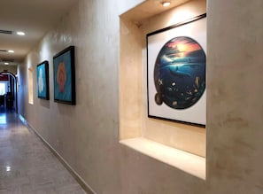Um corredor com obras de arte emolduradas nas paredes e um banco.