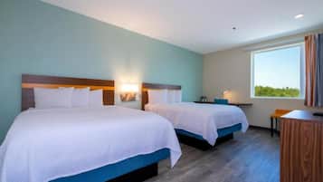A hotel room with two beds, a desk, and a window with curtains.