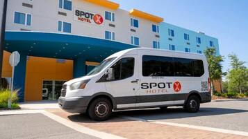 Un furgone bianco parcheggiato di fronte a un hotel con facciata blu e arancione, con la scritta 'SPOT HOTEL'.