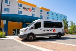 Una furgoneta blanca aparcada davant d'un hotel amb façana blava i taronja, amb la inscripció 'SPOT HOTEL'.