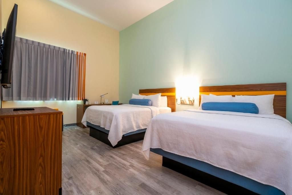 A hotel room with two beds, a desk, and a television.