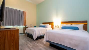 A hotel room with two beds, a desk, and a television.