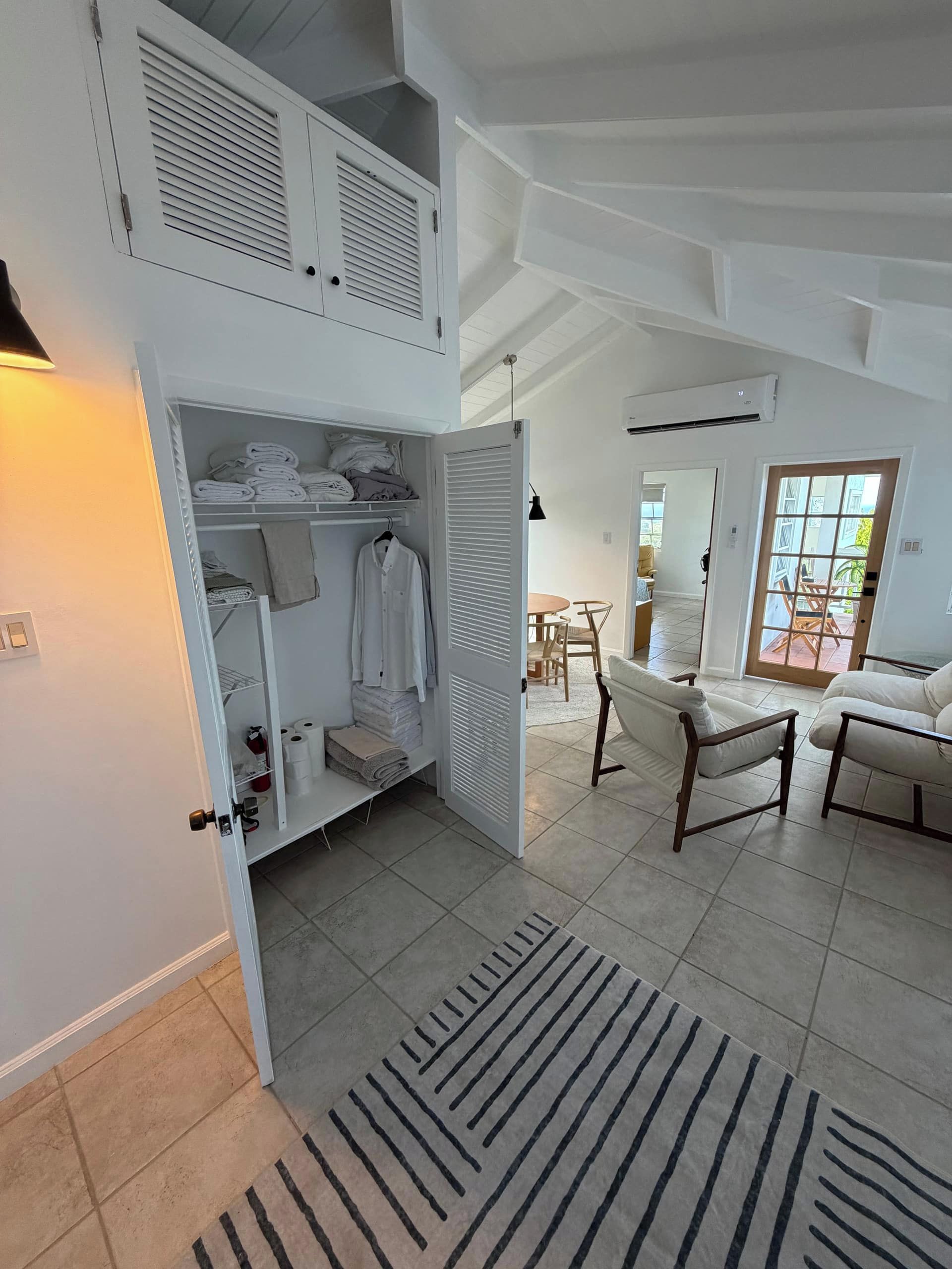 A spacious room with a loft bed, a seating area with two chairs, and a dining table.