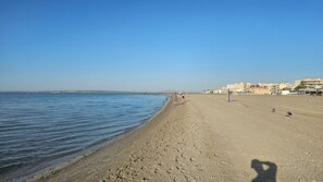 A sandy beach with a clear sky, a calm sea, and buildings in the background. - First floor with a private terrace and a shared pool, just steps from the ocean (Santa Pola)
