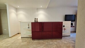 A modern living room with a red cabinet, a glass display unit, and a television. - First floor with a private terrace and a shared pool, just steps from the ocean (Santa Pola)