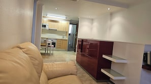 A modern living room with a leather sofa, a kitchen with wooden cabinets, and a built-in TV shelf. - First floor with a private terrace and a shared pool, just steps from the ocean (Santa Pola)