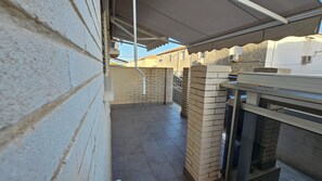 A narrow outdoor corridor with tiled flooring, a brick wall, and a metal railing. - First floor with a private terrace and a shared pool, just steps from the ocean (Santa Pola)