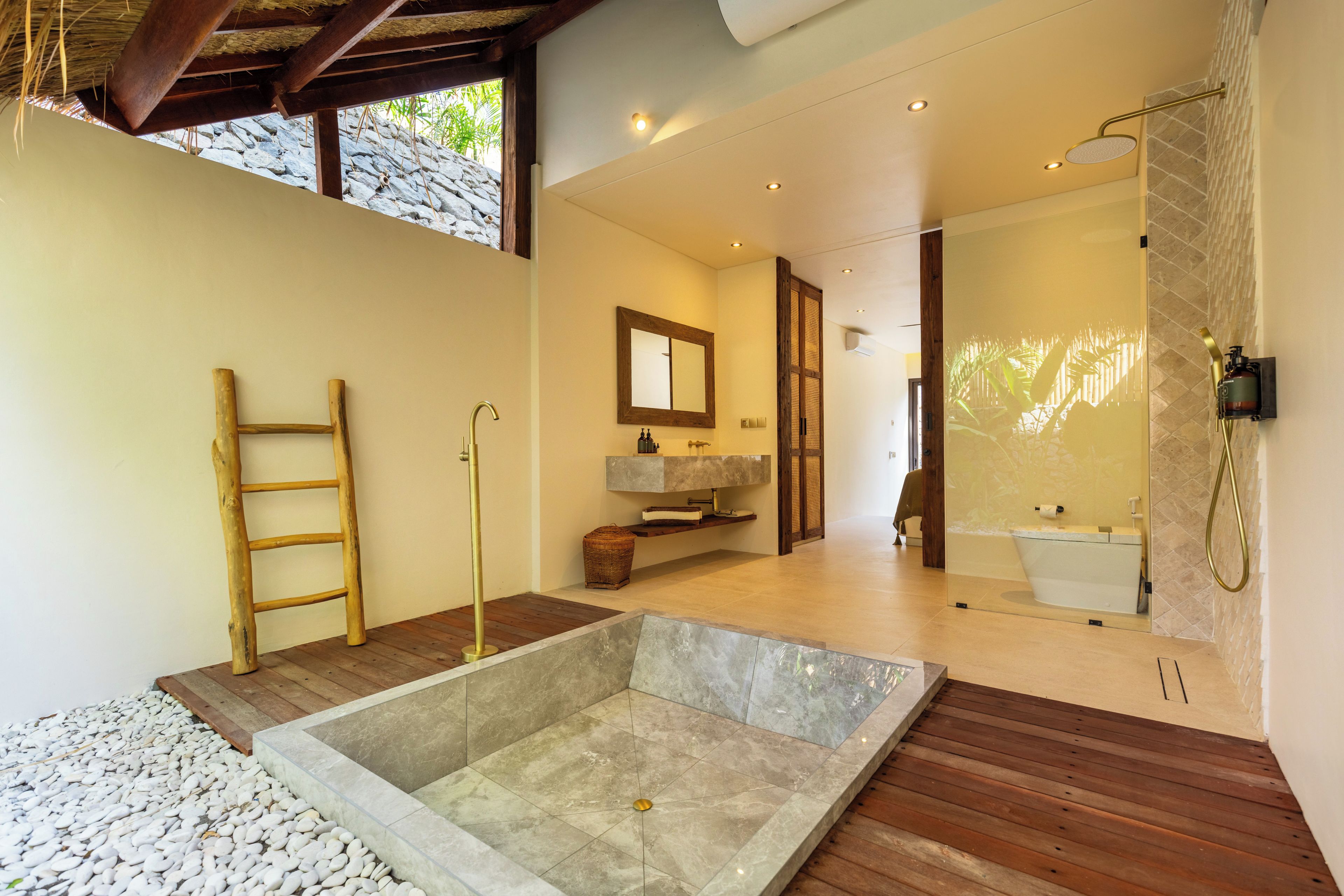 Un baño moderno con un lavabo de piedra, suelo de madera y un espejo grande.