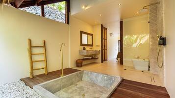 Un baño moderno con un lavabo de piedra, suelo de madera y un espejo grande.