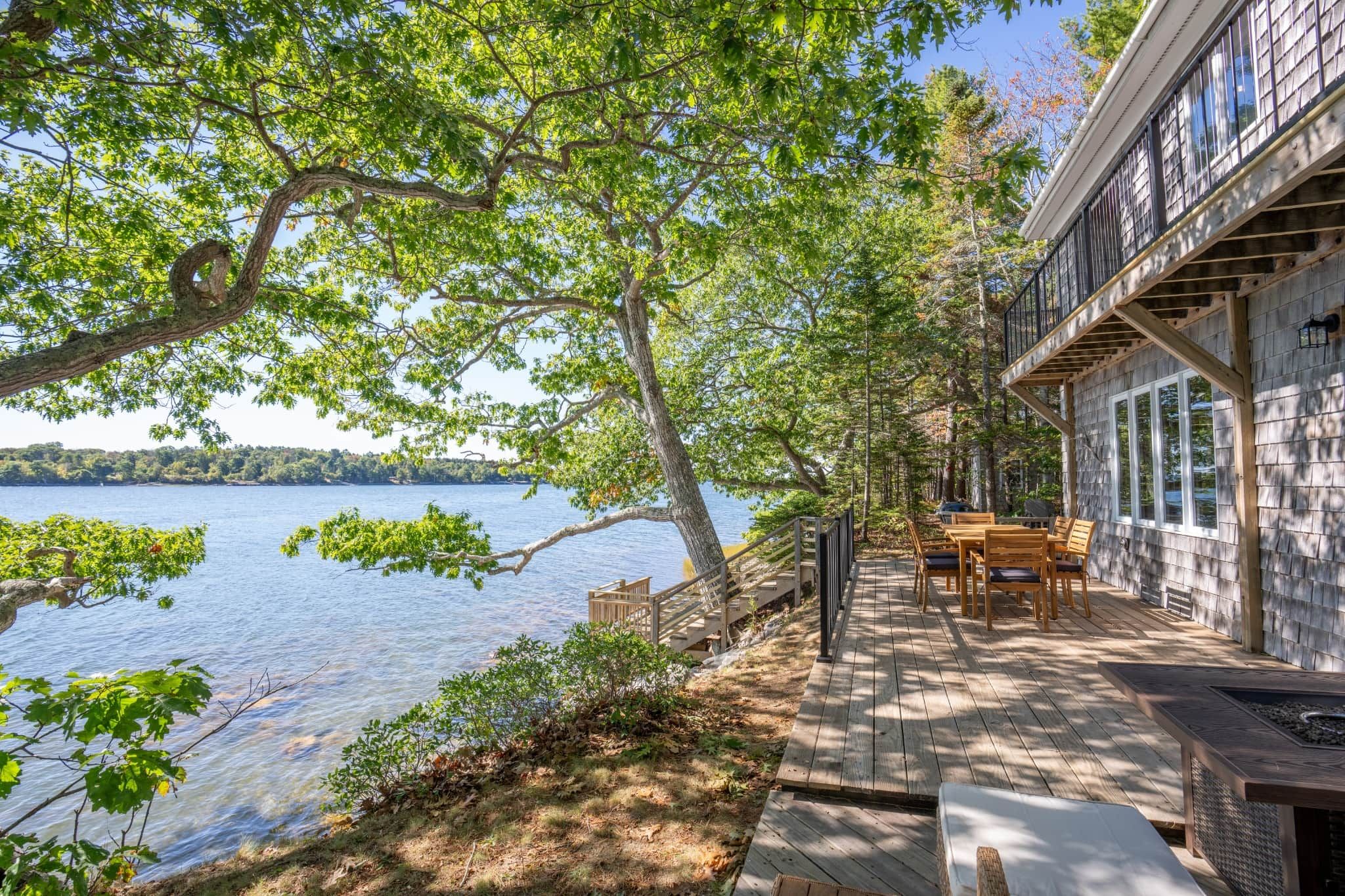 A lakeside property with a deck, outdoor seating, and a view of the water.