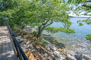 Eine Holzterrasse mit Sitzgelegenheit mit Blick auf einen See und einen Baum.