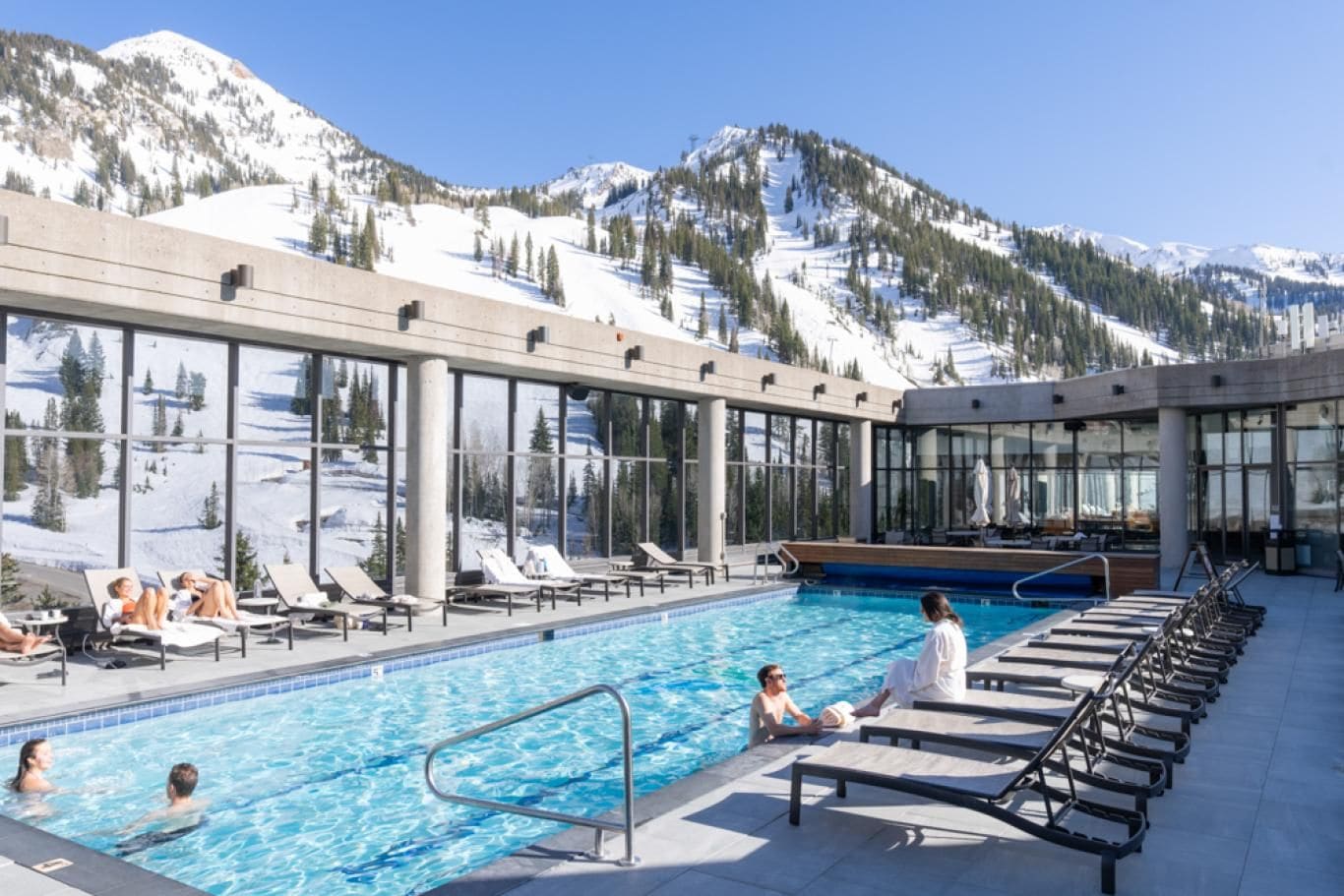 A pool area with lounge chairs and a view of snow-covered mountains.