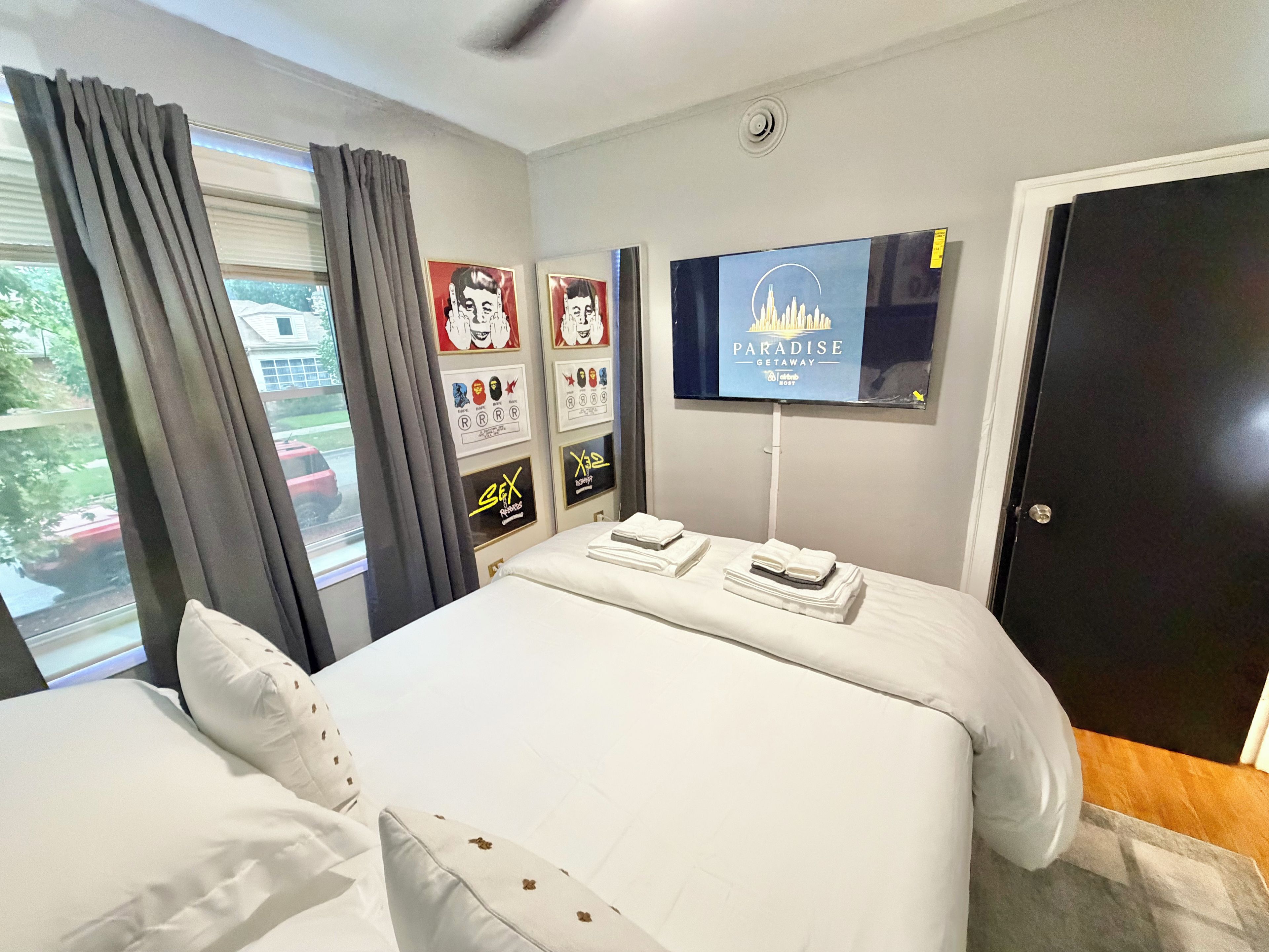 A hotel room with a bed, a TV mounted on the wall, and a window with curtains.
