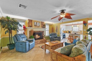 A living room with a fireplace, leather chairs, a sofa, and a ceiling fan. - Escape to your private Poolside Paradise - Backyard Oasis w/pool & palapa.  Min (Galveston)
