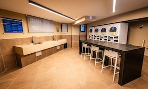 A public restroom with a long sink, multiple toilets, and a row of washing machines. - Cozy 1-bedroom apartment in adorable Santiago with fitness room (Santiago)