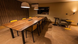 A conference room with a long wooden table, yellow chairs, and pendant lighting. - Cozy 1-bedroom apartment in adorable Santiago with fitness room (Santiago)