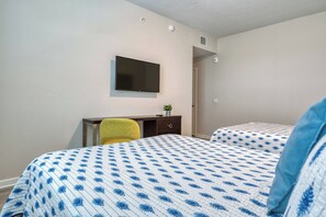 Une chambre d’hôtel avec un lit, un bureau, une chaise et un téléviseur fixé au mur.