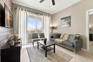 A modern living room with a sofa, chairs, a coffee table, and a TV mounted on the wall. - Orlando 3BR Condo, Space, Comfort and Location (Orlando)