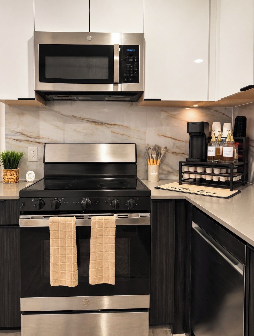 A modern kitchen with a stainless steel microwave, oven, and stovetop. There is a coffee maker and a spice rack on the counter.