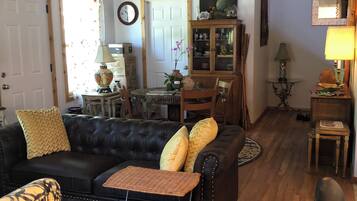 A living room with a black leather sofa, a wooden coffee table, and a patterned armchair.