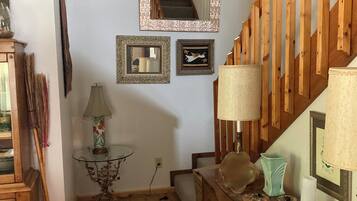 A wooden staircase with a railing, a small table with a lamp, and a mirror on the wall.