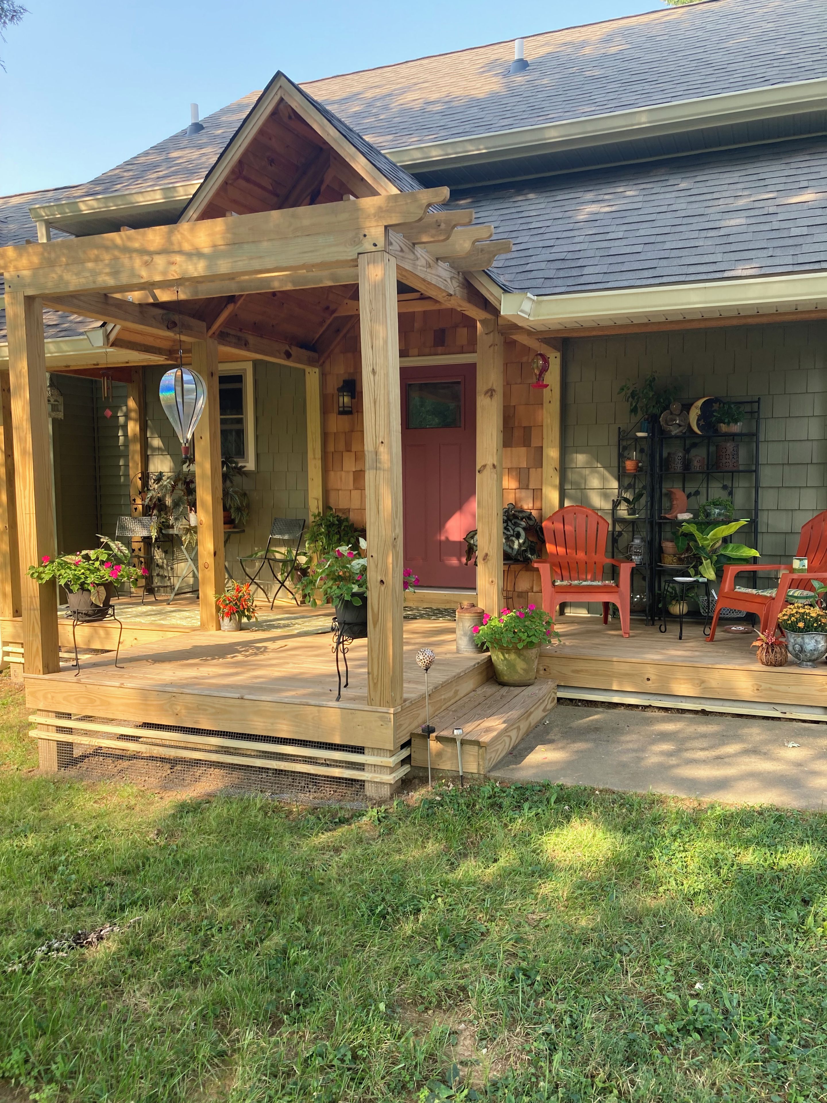 A wooden porch with outdoor seating and potted plants.