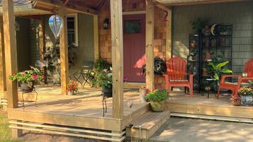 A wooden porch with outdoor seating and potted plants.