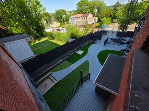 A residential backyard with a paved patio, a wooden deck, and a fenced area.
