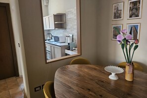 A dining area with a wooden table, yellow chairs, a white cake stand, and a vase with flowers. - Montefiori Luxury Suite (Bologna)